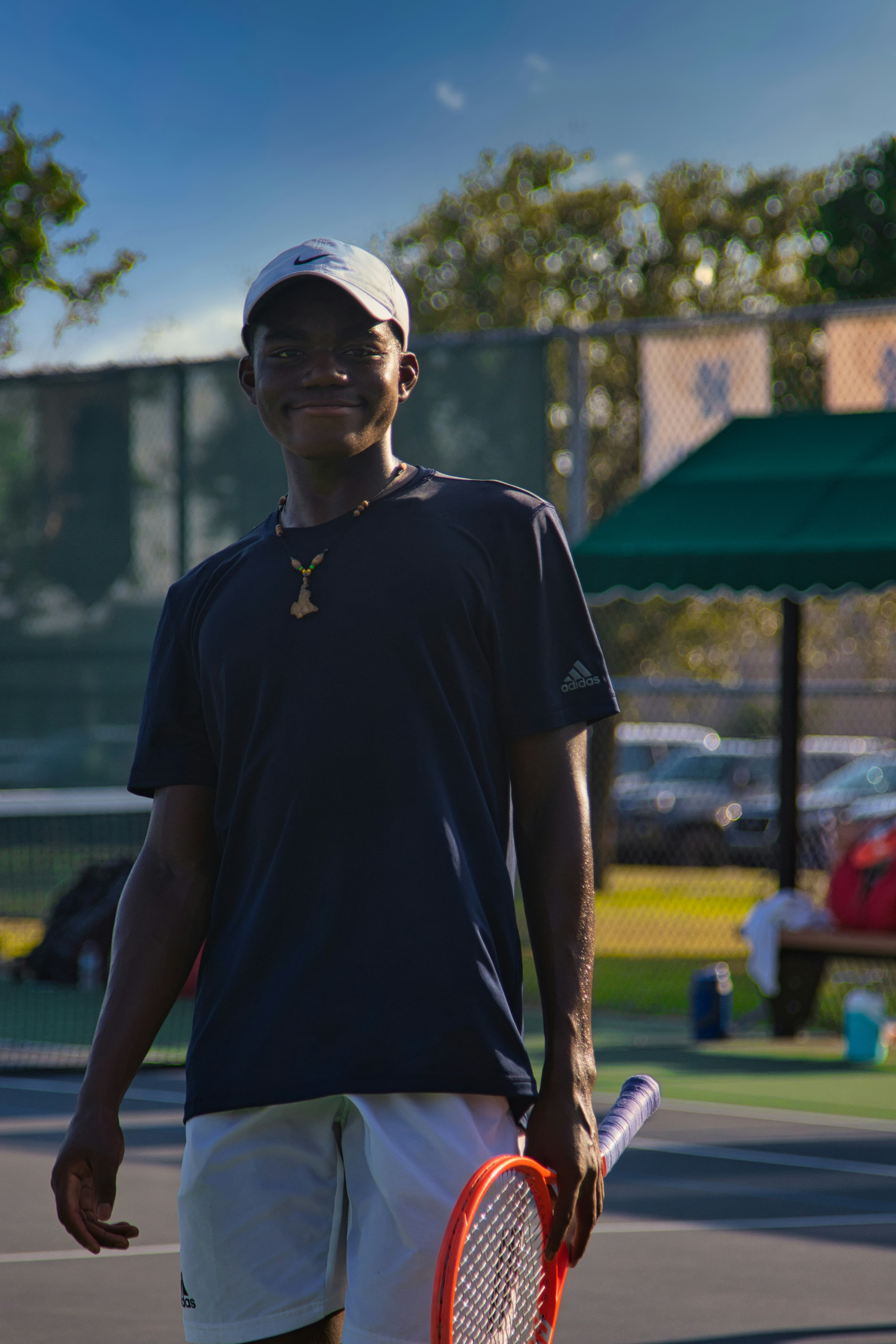 Man in black polo shirt standing on a grass tennis court